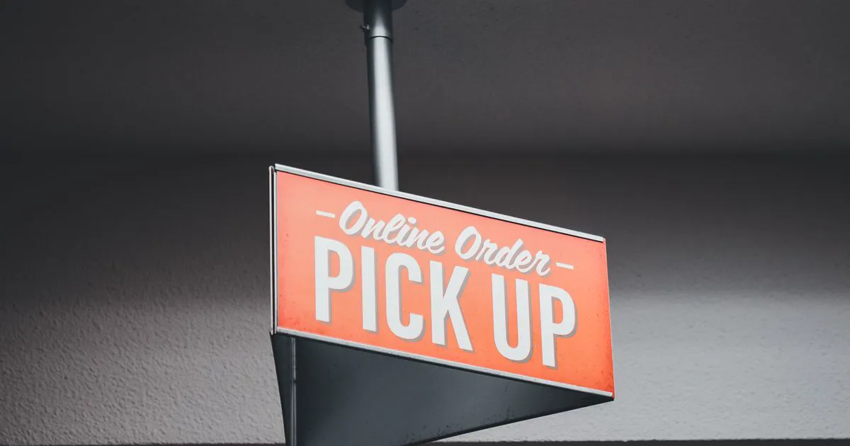 An orange overhead sign in a restaurant reading Online Order Pick Up, marking the takeout collection area